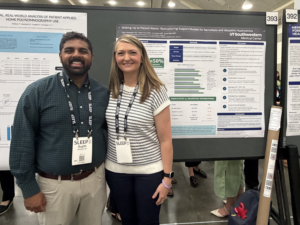 Man and woman standing in front of research poster smiling