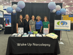 5 women standing at a exhibitor booth with Wake Up Narcolepsy materials
