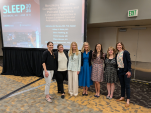 7 women standing together in front of a screen with presentation session information